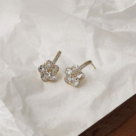 Angled view of the pair of gold flower stud earrings.