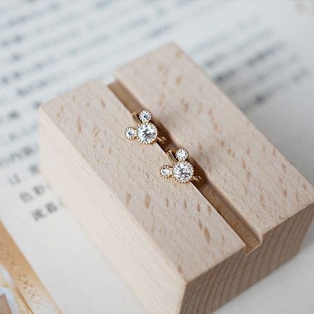 The huggie hoop earrings presented on a wooden box, emphasizing the quality materials and sparkling gemstones.