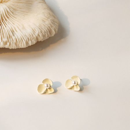 A pair of gold flower earrings with pearl centers, showing a color variation.