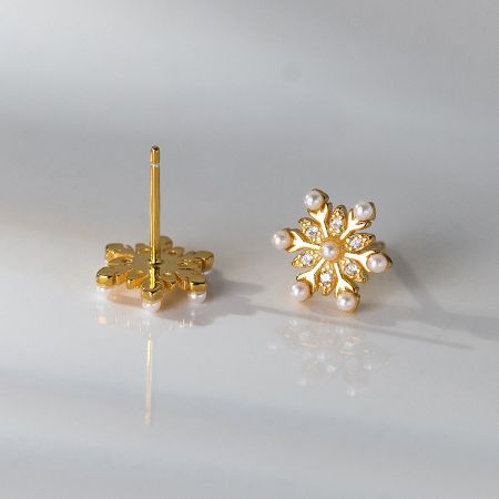 A different perspective on the gold snowflake earring, emphasizing its lustrous pearl and brilliant gems.