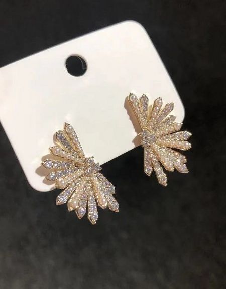 A close-up shot of the gold-toned pearl fan earrings, emphasizing the sparkle of the embedded crystals.