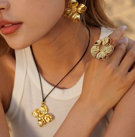 Stainless Steel 18K Gold Plated Flower Set - A model showcasing the Stainless Steel 18K Gold Plated Flower Jewelry Set, highlighting the intricate design of the necklace, earrings, and ring.