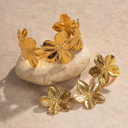 Stainless Steel Flower Set - Elegant Stainless Steel Flower Jewelry Set with gold plating, featuring matching earrings and bracelet displayed on a decorative stone.