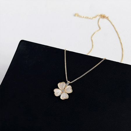 Elegant gold necklace with a flower pendant featuring four white cat-eye stone petals.