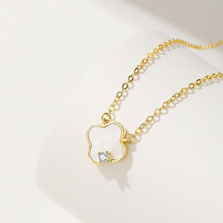 Detailed view of the gold-finished four-leaf clover pendant, highlighting the mother-of-shell inlay.