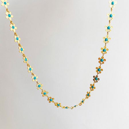 A close-up view of the gold necklace highlighting the turquoise-colored centers of the flower charms.