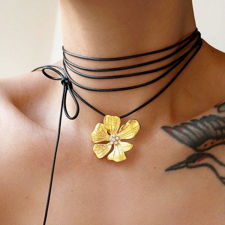 Gold hibiscus flower pendant necklace worn on a model.