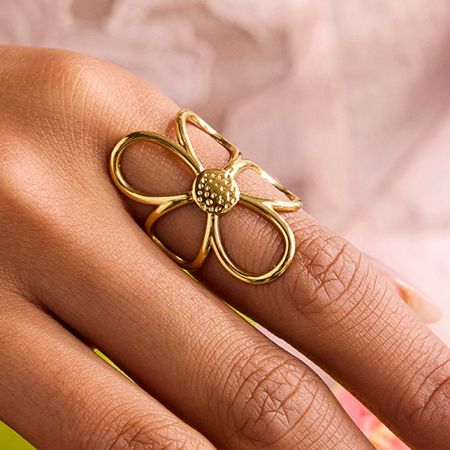 Close-up of the gold stainless steel daisy ring on a finger.