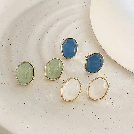 An assortment of the 14K gold plated resin earrings on a decorative plate.