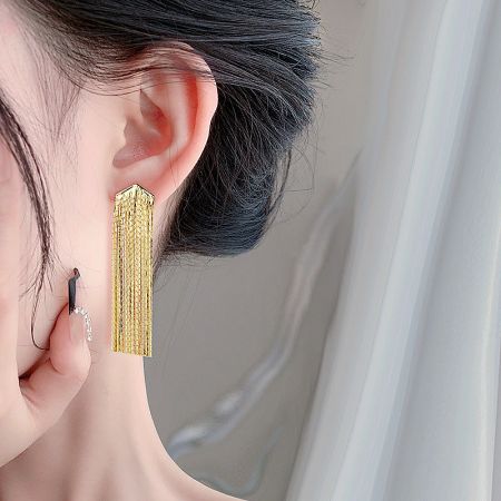 Model wearing the gold exaggerated long chain tassel earring to showcase its length and style.