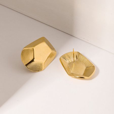 A pair of gold geometric pentagon earrings displayed on a white surface.