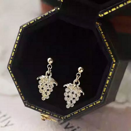 The gold grape earrings elegantly presented in a luxurious black velvet jewelry box.