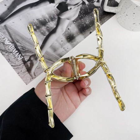 A detailed product shot of a large metal hair clamp clip in a luxurious gold finish.