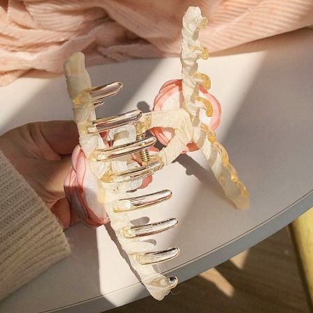 Detailed view of the gold-tone clip mechanism of the camellia hair claw.