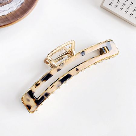 Detailed view of a classic tortoiseshell pattern acetate hair clip with a shiny gold finish.