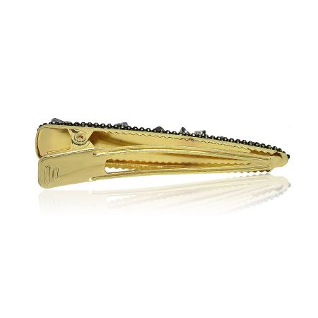 Side view of the gold hair clip with dark stones.