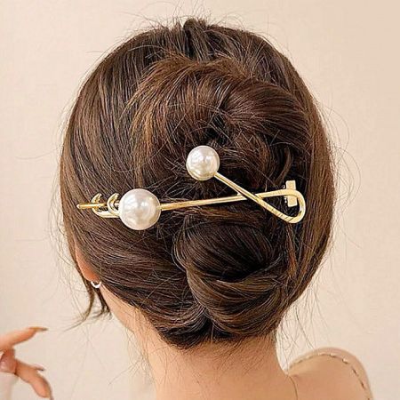 Close-up shot highlighting the twisted design and pearl accents of the gold hair clip.