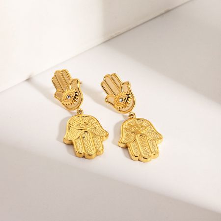 Detailed shot of the Hamsa hand earring with a central eye motif featuring a small gemstone.