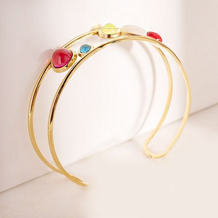 Close-up view of the colorful gemstones on the gold-tone cuff bracelet.