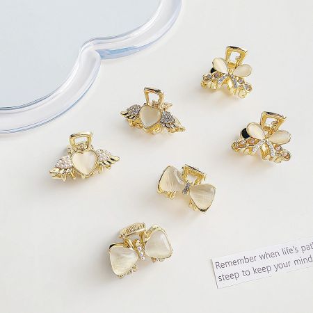 Assortment of delicate mini hair clips in gold, shaped like hearts and bows, embellished with pearls.