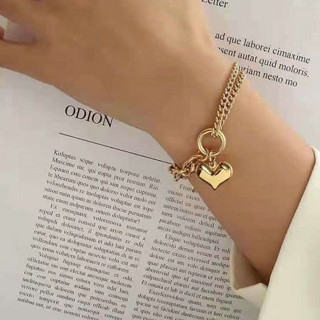 The Gold Puff Heart Chain Link Bracelet displayed on a white surface, highlighting its reflective finish.