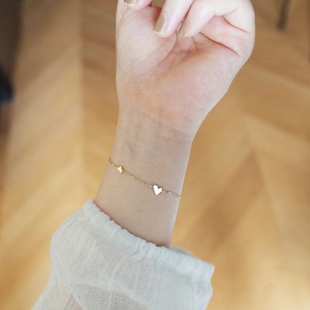 Lifestyle view of the gold heart charm bracelet on a wrist.