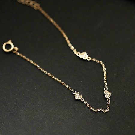 Detailed studio shot of the gold heart charm bracelet, showing its fine craftsmanship.