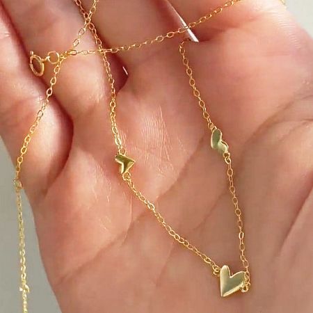 The triple heart necklace displayed flat to show its structure.