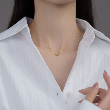 Close-up of the gold heart pendant necklace showcasing a brilliant blue stone.