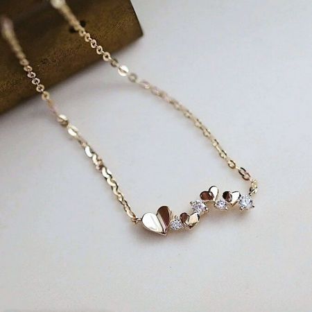 Close-up of the gold heart necklace with alternating solid and gemstone hearts.