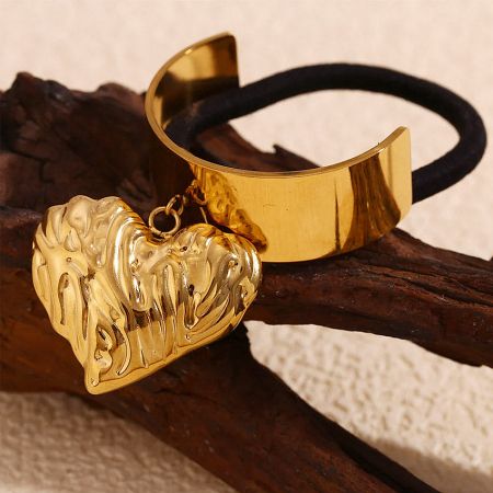 Detailed view of the gold heart charm and the cuff wrap design of the hair tie.