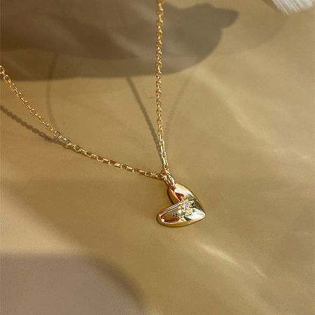 The 18K gold heart pendant necklace displayed on a neutral background.