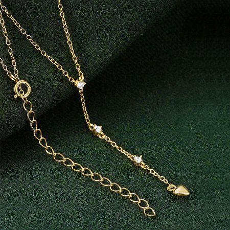 Detailed view of the gold heart charm pendant with delicate stone accents.