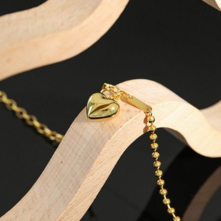 Elegant gold heart necklace displayed on a wooden surface, highlighting its glossy finish.