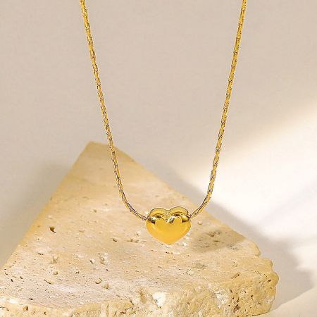 Close-up view of the tiny gold heart pendant on its chain.