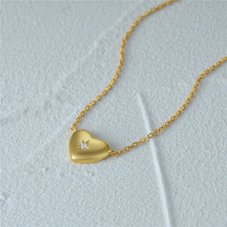 Close-up of the gold heart pendant necklace with a central zircon stone.