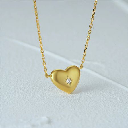 Another angle of the gold heart pendant necklace, focusing on the central gemstone.