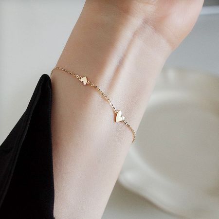 925 Sterling Silver Gold-Plated Heart Link Chain Bracelet (Set of 5) - A close-up of the 925 Sterling Silver Gold-Plated Heart Link Chain Bracelet worn on a wrist, showcasing its delicate design.