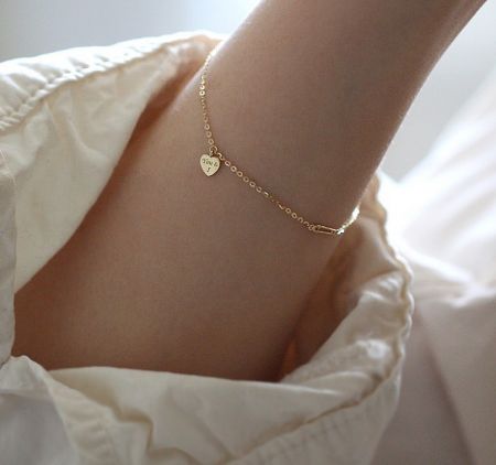 Detailed view of the gold-plated heart charm bracelet, showing the lobster clasp and chain construction.
