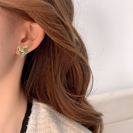 Model wearing the 14K gold plated brass heart stud earring to show scale and style.