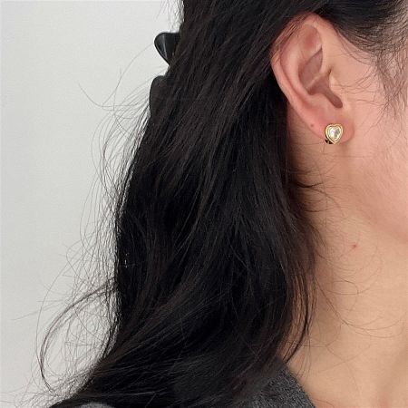 A model wearing the 18K gold-plated heart huggie earring to show its fit and style.