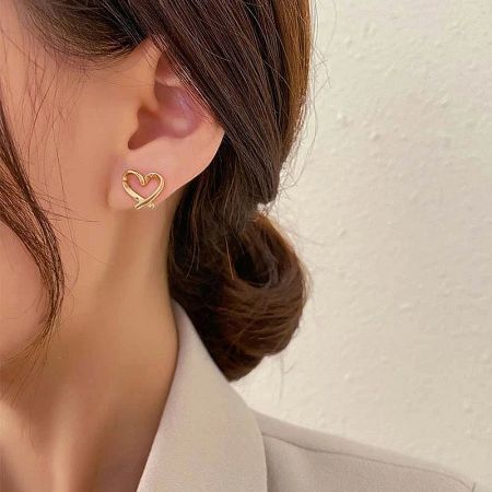 Model wearing the gold heart-shaped non-pierced ear clip earring.