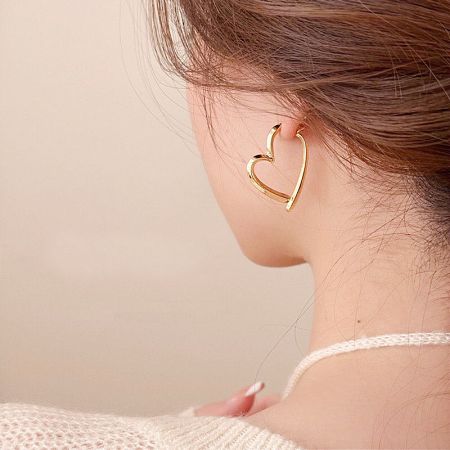 Close-up of a model wearing the gold geometric heart drop earring.