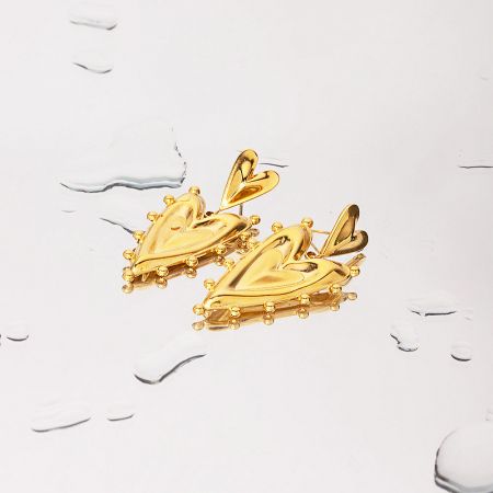 Detailed product shot of the polished gold heart-shaped earrings.