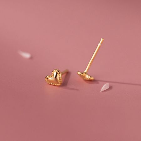 Close-up of a gold heart-shaped earring highlighting its textured edges and warm tone.