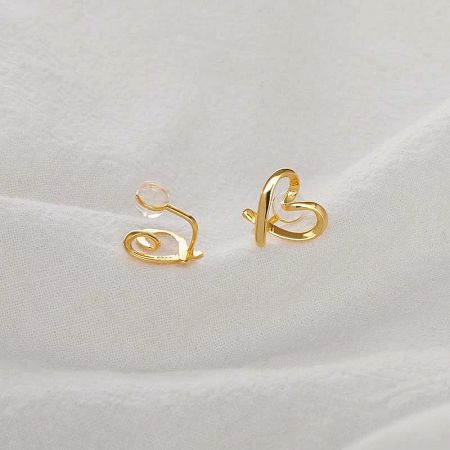 Detailed view of the gold heart-shaped ear clip featuring a swirling design.