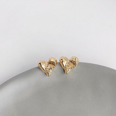 Detailed shot of the textured surface on the gold heart-shaped earrings.