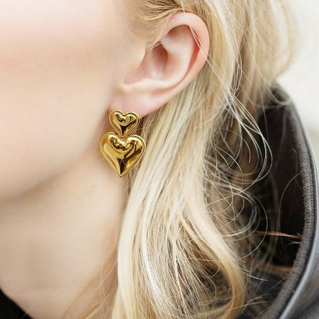 Model wearing the gold stainless steel double heart statement drop earrings.