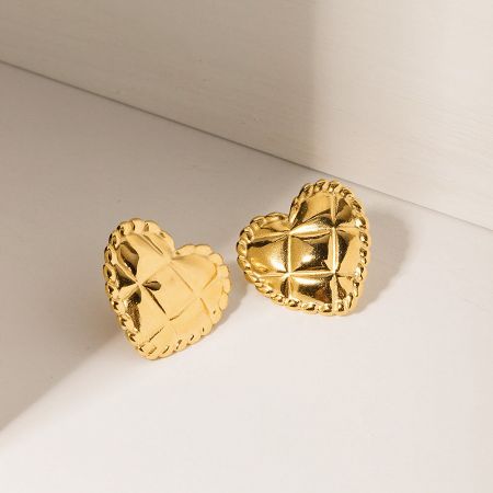 Close-up view of the textured plaid pattern on the gold heart-shaped stud earrings.