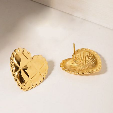 Detailed shot of the intricate design and beaded edges of the gold heart earrings.